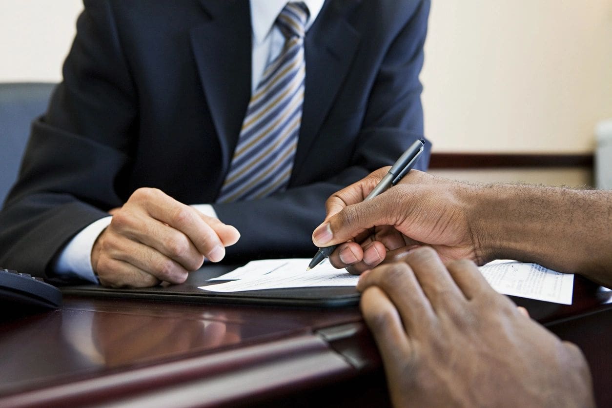 A man in a suit is writing on paper