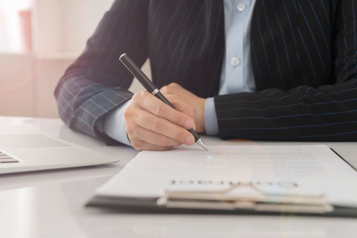 A person writing on paper with a pen.