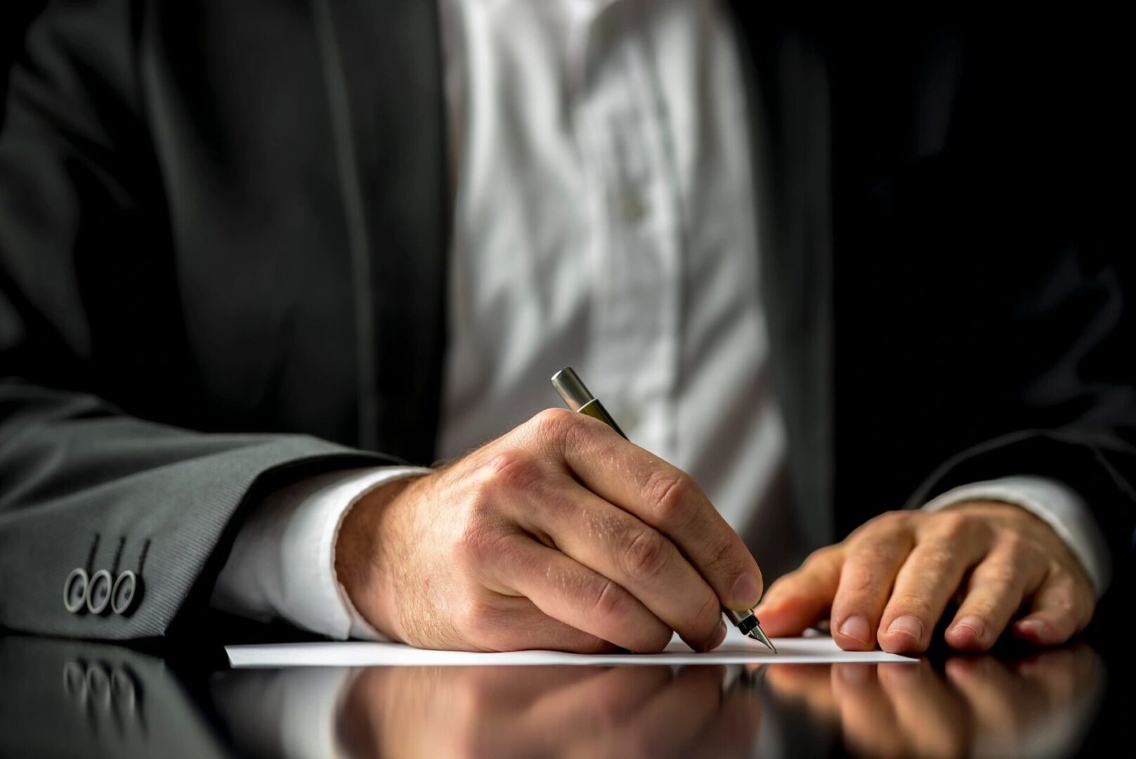 A person writing on paper with a pen.