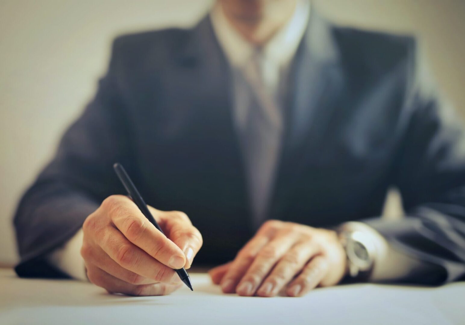 A man in a suit writing on paper.